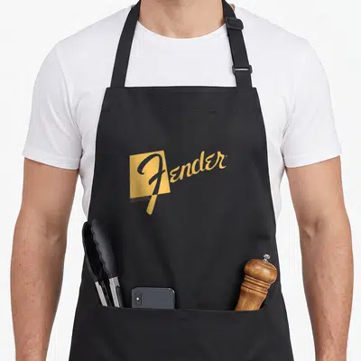 Tablier de cuisine noir avec le logo Fender Retro Text Logo stylisé en jaune moutarde sur fond uni.