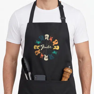 Tablier de cuisine noir avec un motif circulaire de guitares électriques colorées et le logo Fender en blanc.
