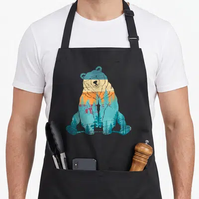 Tablier de cuisine noir avec illustration d'ours grizzly contenant des arbres et un ciel orange retro