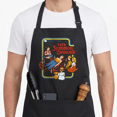 Tablier de cuisine noir avec illustration rétro enfants autour d'un pentagramme et texte Let's Summon Demons en rouge.