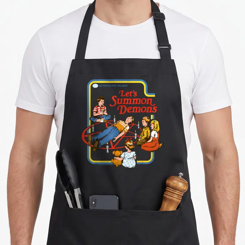 Tablier de cuisine noir avec illustration rétro enfants autour d'un pentagramme et texte Let's Summon Demons en rouge.