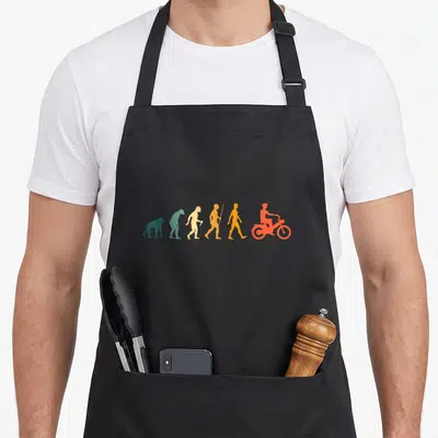 Tablier de cuisine noir avec illustration colorée de l'évolution humaine terminant par un cyclomoteur orange.
