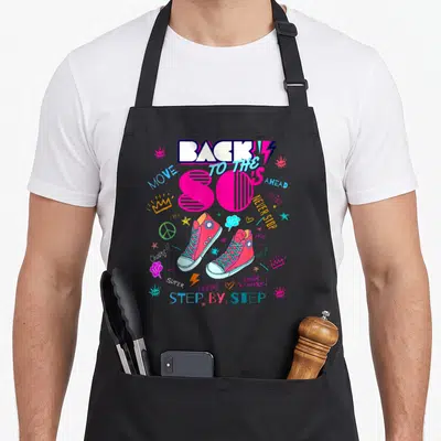 Tablier de cuisine noir orné de sneakers roses, d'éclairs et du texte Back to the 80's en lettres colorées.