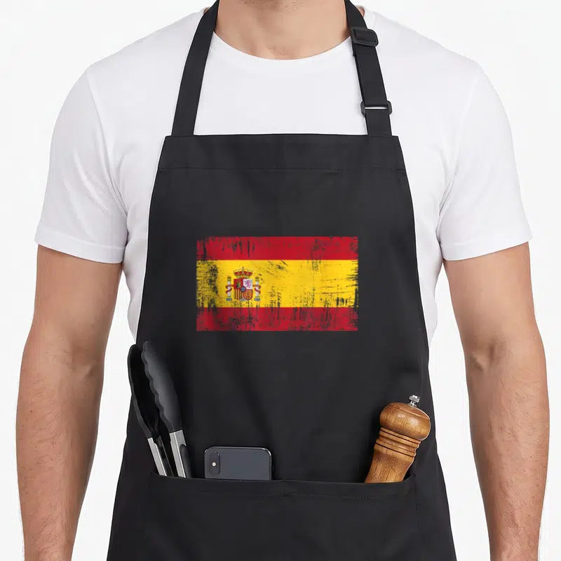 Tablier de cuisine noir avec drapeau espagnol vintage aux couleurs rouges et jaunes délavées.