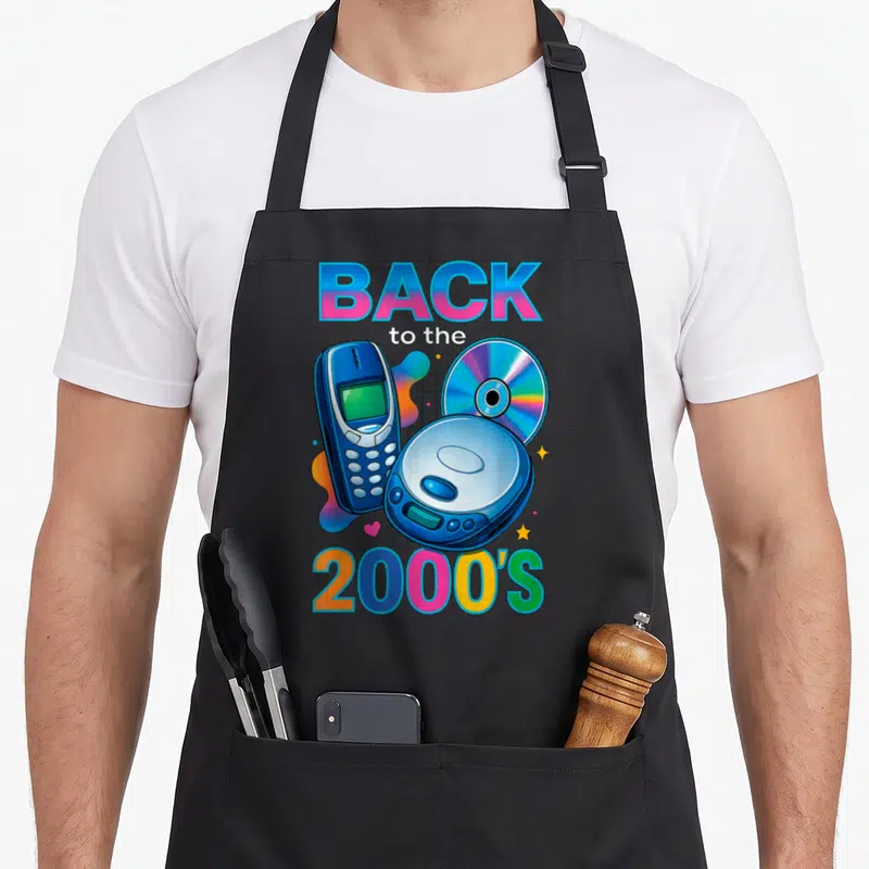Tablier de cuisine noir avec illustration d'un téléphone portable, d'un disque compact et du texte Back to the 2000's en couleurs vives.