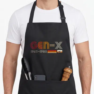 Tablier de cuisine noir avec typographie Gen-X colorée et illustration de cassette audio rétro.