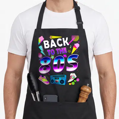 Tablier de cuisine noir avec motif Back to the 80s, boombox bleue, patins à roulettes et étoiles colorées sur fond uni.
