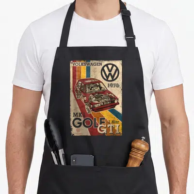Tablier de cuisine noir avec illustration rétro d'une voiture rouge et le logo Volkswagen en haut à droite.