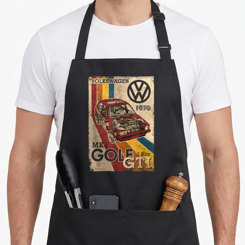 Tablier de cuisine noir avec illustration rétro d'une voiture rouge et le logo Volkswagen en haut à droite.