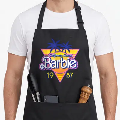 Tablier de cuisine noir avec le logo rétro Barbie California Dream 1987 et des palmiers bleus.