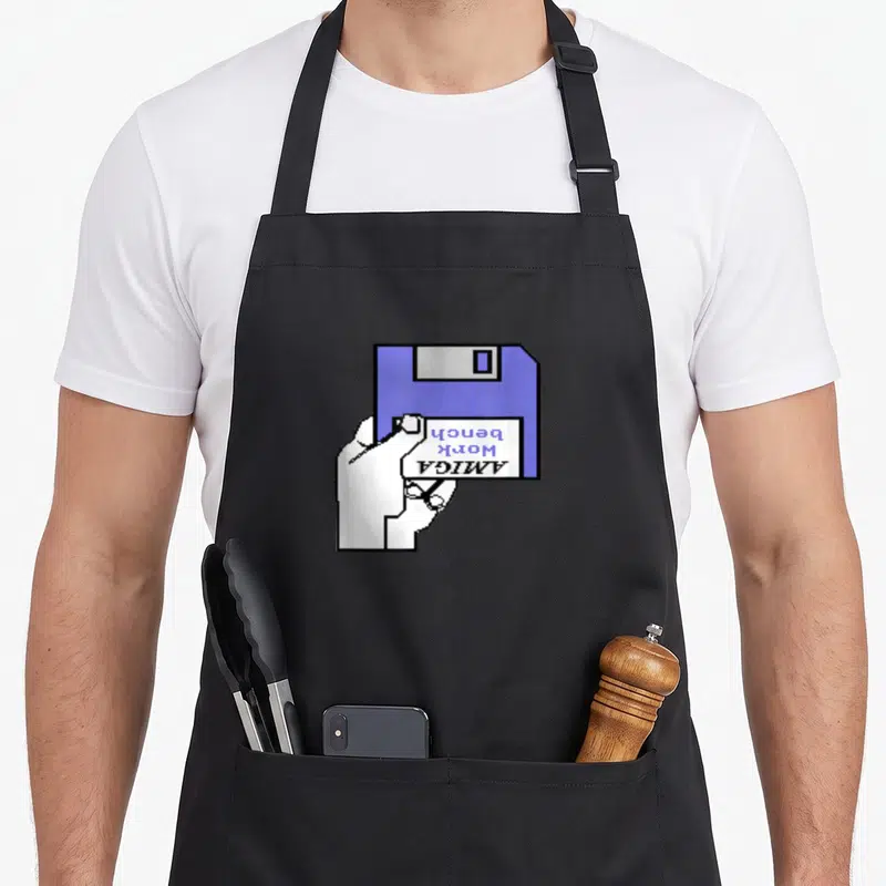 Tablier de cuisine noir avec illustration pixel art d'une main tenant un disque Amiga Workbench violet.
