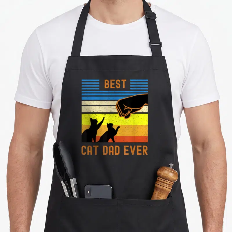 Tablier de cuisine noir avec design vintage Best Cat Dad Ever et poignée de main entre humain et chats en silhouette.