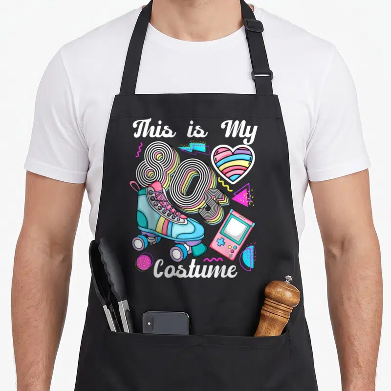 Tablier de cuisine noir avec illustration colorée de patins, Console portable et texte This is My 80 Costume en style rétro.