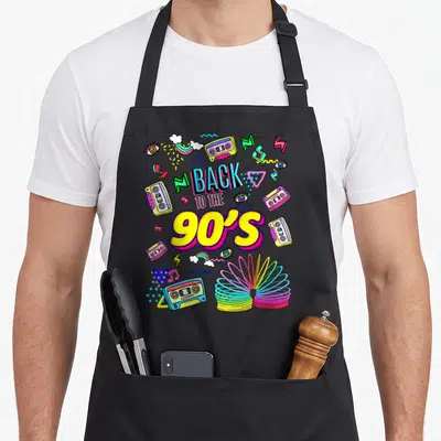 Tablier de cuisine noir avec illustration colorée Back to the 90's, cassettes audio et slinky multicolore.