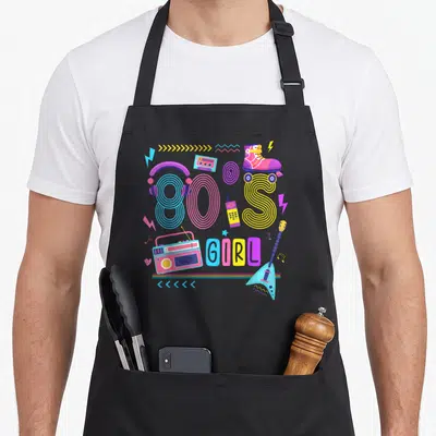 Tablier de cuisine noir avec illustration colorée 80s Girl featuring boombox, headphones, roller skates and guitar in retro style.
