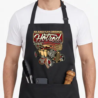 Tablier de cuisine noir avec une illustration de Hotrod dorée, le texte Hotrod Rebel et un moteur détaillé en style vintage.