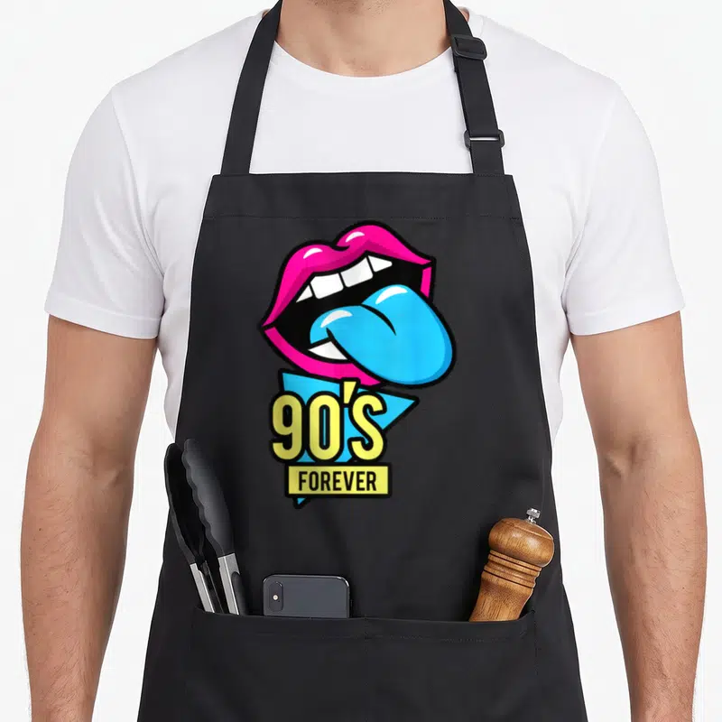 Tablier de cuisine noir avec lèvres roses, langue bleue et inscription 90's Forever en jaune.