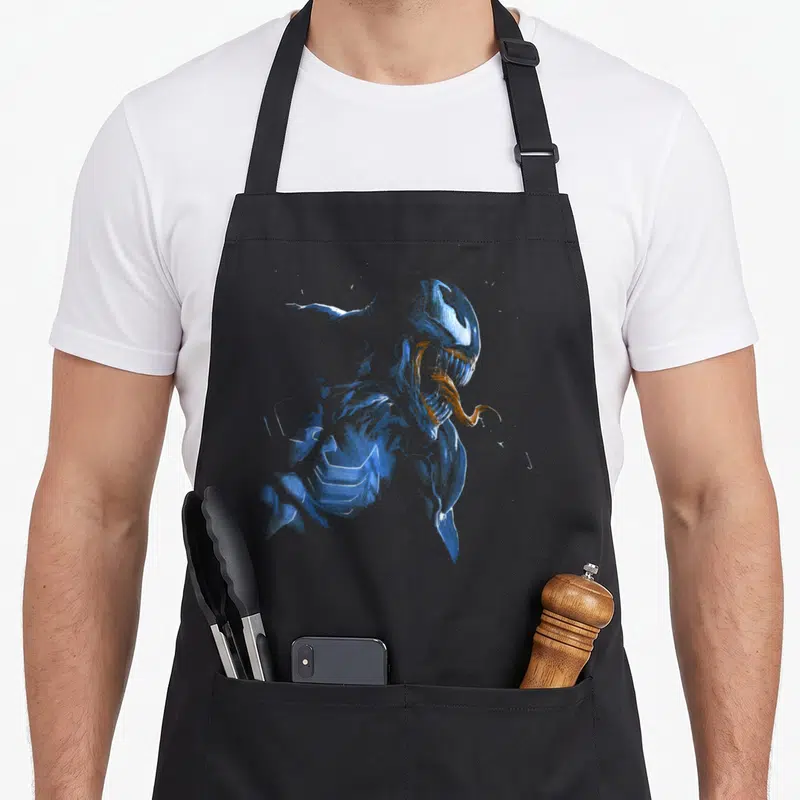 Tablier de cuisine noir avec illustration rétro du symbiote Venom en bleu et langue orange, tête penchée vers le bas.