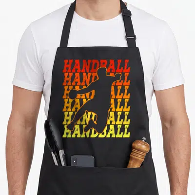 Tablier de cuisine noir avec silhouette sautante de gardien de handball sur texte HANDBALL répété en dégradé orange et jaune rétro.