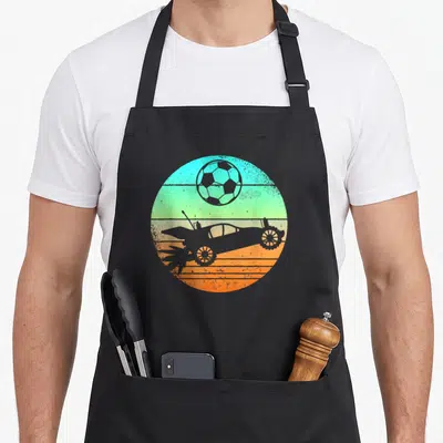 Tablier de cuisine noir avec illustration circulaire d'une voiture téléguidée et d'un ballon de football sur fond dégradé.