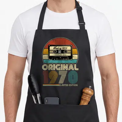 Tablier de cuisine noir avec illustration de cassette audio rétro et typographie colorée 1970.