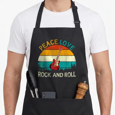 Tablier de cuisine noir avec illustration guitare électrique rouge et texte Peace Love Rock and Roll en style rétro.