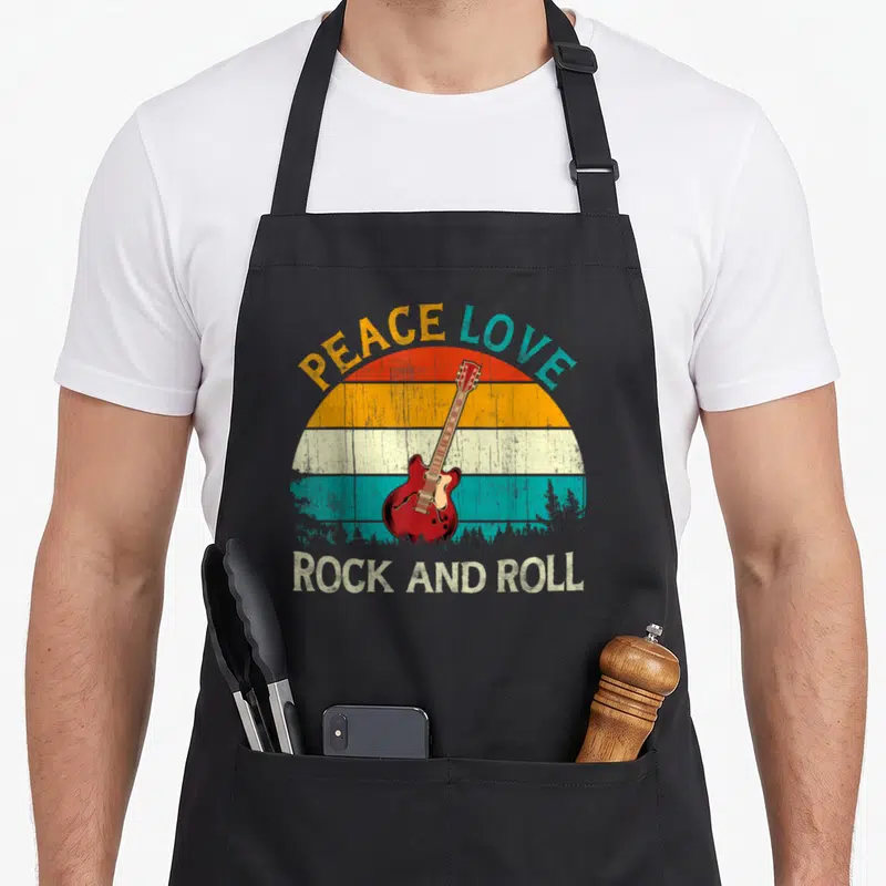 Tablier de cuisine noir avec illustration guitare électrique rouge et texte Peace Love Rock and Roll en style rétro.