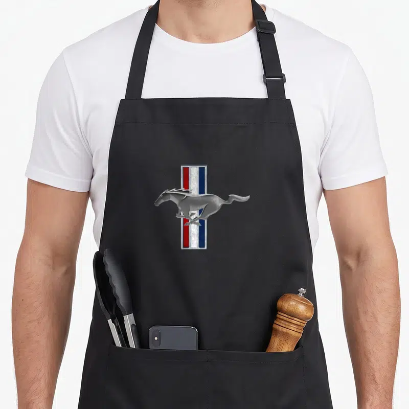 Tablier de cuisine noir avec logo Mustang et cheval galopant sur bandes colorées verticales.
