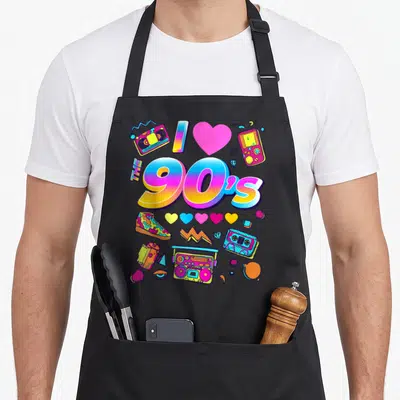 Tablier de cuisine noir avec le texte The 90's et des illustrations rétro comme une boombox, une cassette et des cœurs colorés.