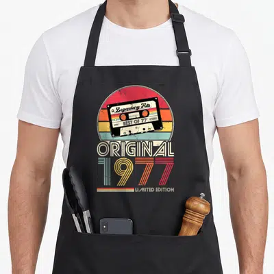 Tablier de cuisine noir avec illustration de cassette audio rétro et texte original 1977 limited edition sur fond arc-en-ciel délavé