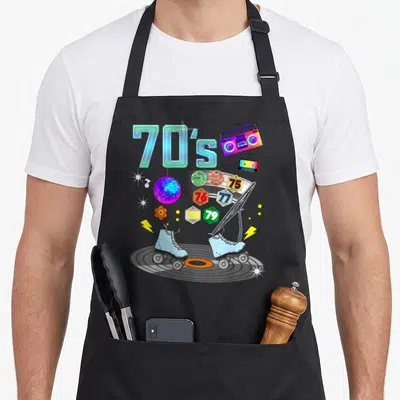 Tablier de cuisine noir avec illustration de patins, disque et boombox années 70.