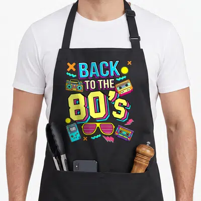 Tablier de cuisine noir avec inscription Back to the 80's entourée d'une boombox, de cassettes et de lunettes roses.