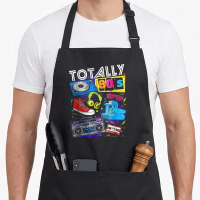 Tablier de cuisine noir avec illustration coloréeTotally 80s, boombox, platine vinyle et sneakers rouges.