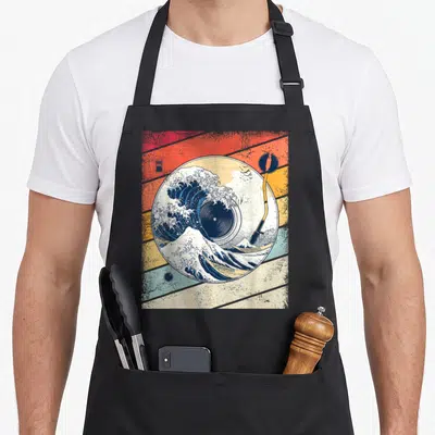 Tablier de cuisine noir avec illustration d'un disque vinyle transformé en Grande Houle de Kanagawa sur fond rayé coloré.