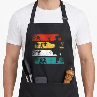 Tablier de cuisine noir avec silhouettes de combattants sur bandes rouges jaunes blanches et bleues style rétro délavé