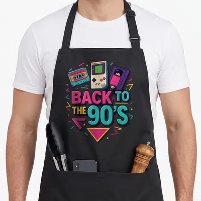 Tablier de cuisine noir avec illustration rétro années 90 montrant une cassette, une console et une VHS autour du texte Back to the 90s.