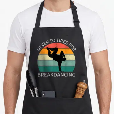 Tablier de cuisine noir avec silhouette de breakdanceur et texte blanc sur fond de soleil rayé multicolore