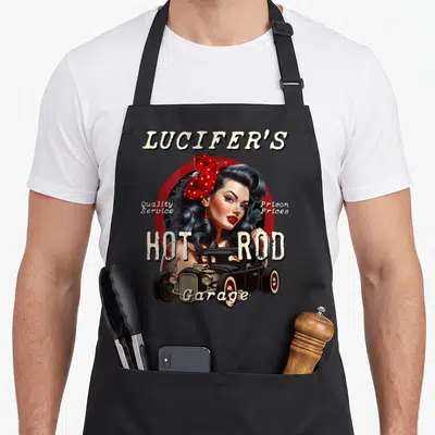 Tablier de cuisine noir avec une illustration de pinup rockabilly coiffée d'un bandana rouge à pois blancs devant une voiture Hot Rod noire.
