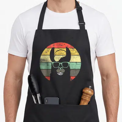 Tablier de cuisine noir avec illustration d'un alpaga rétro aux lunettes vertes et fond coloré texturé.