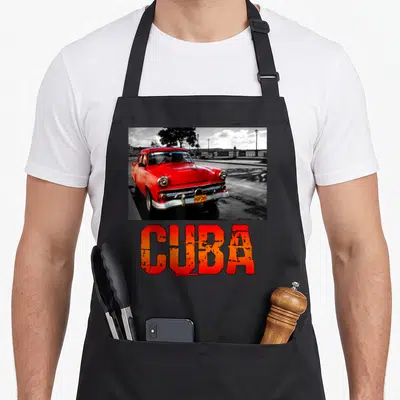Tablier de cuisine noir avec une voiture rouge classique et le mot CUBA en lettres orange délavées.