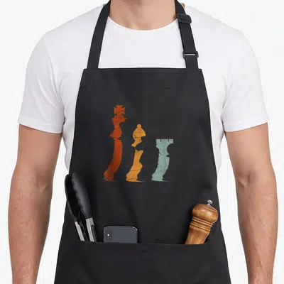 Tablier de cuisine noir avec trois pièces d'échecs colorées au style rétro et texturé.