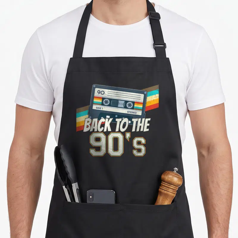 Tablier de cuisine noir avec illustration de cassette audio et texte Back to the 90's coloré.