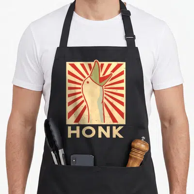 Tablier de cuisine noir avec illustration rétro d'une main d'oie et le texte HONK en lettres capitales crème sur fond de rayons rouges.