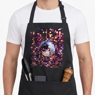 Tablier de cuisine noir avec une boule disco argentée suspendue sur fond de lumières floues multicolores.