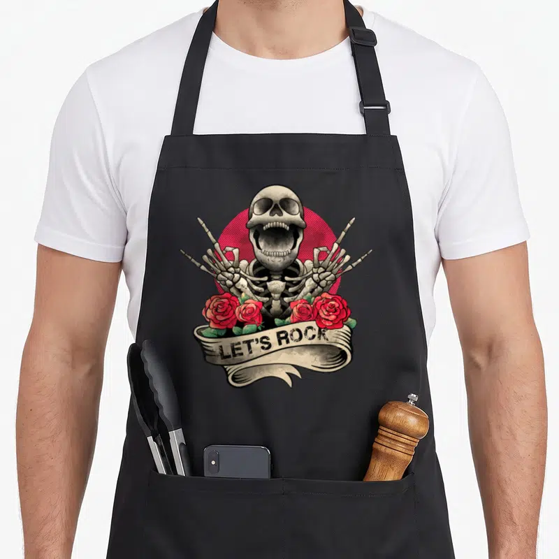 Tablier de cuisine noir avec un squelette criant, des roses rouges et le texte Let's Rock sur une bannière.