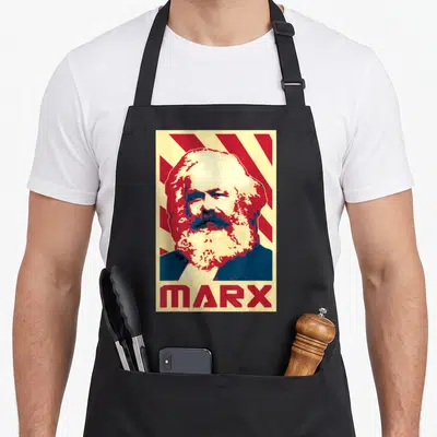 Tablier de cuisine noir avec portrait stylisé de Karl Marx et le mot MARX en rouge sur fond rayé jaune et rouge.