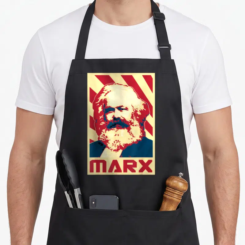 Tablier de cuisine noir avec portrait stylisé de Karl Marx et le mot MARX en rouge sur fond rayé jaune et rouge.