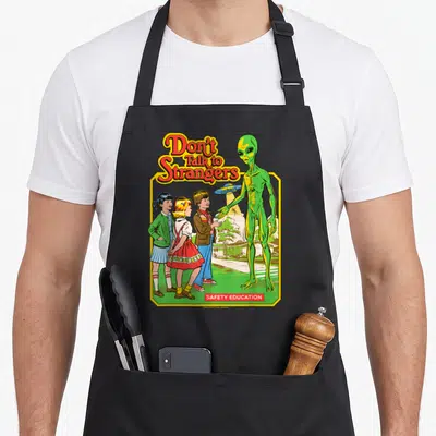 Tablier de cuisine noir avec une illustration retro montrant des enfants et un alien vert sous le texte Don't Talk to Strangers.