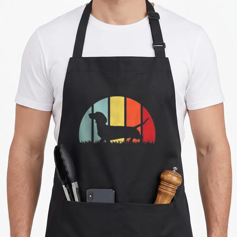 Tablier de cuisine noir avec silhouette de chien saucisse sur fond arc-en-ciel coloré retro