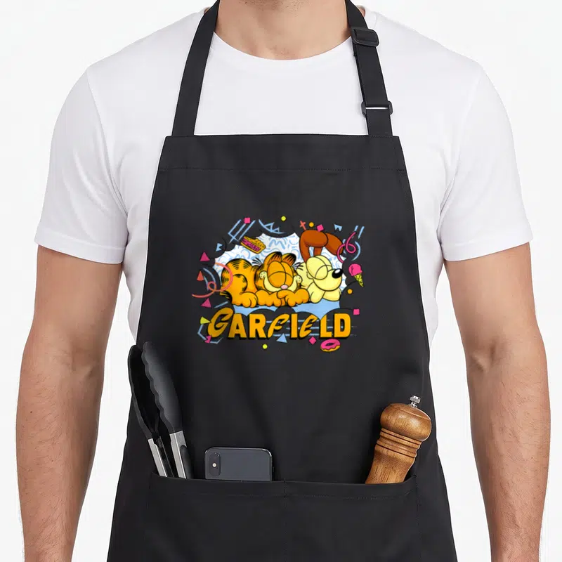 Tablier de cuisine noir avec illustration colorée de Garfield et Odie dormant au milieu de motifs géométriques rétro et du texte Garfield.